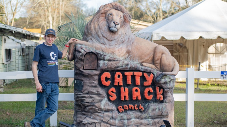 A Catty Shack Ranch caretaker stands in front of the sanctuary's front sign