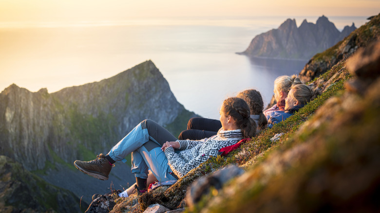 Hikers lying down on a hillside watching a sunset