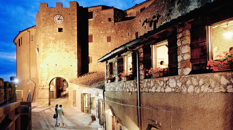 A couple walking evening streets along a wall in Capalbio, Tuscany