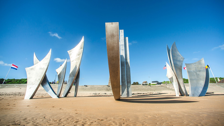 Silver art installations on a beach against a blue sky.