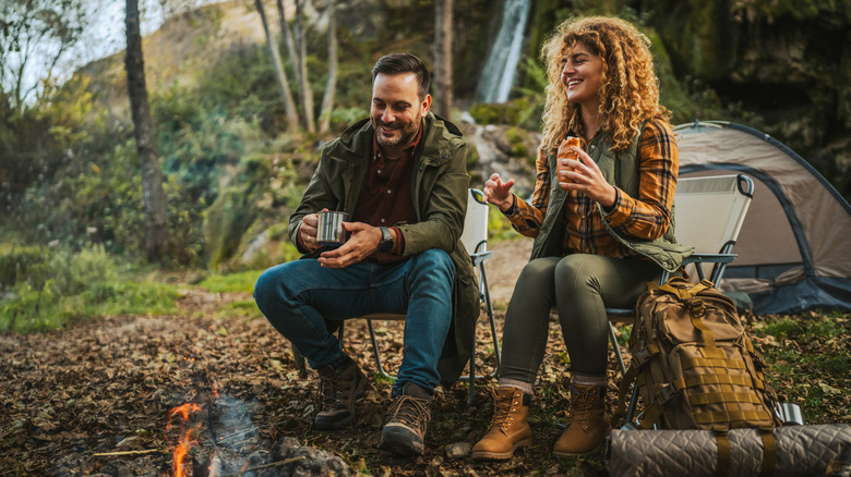 A couple sitting at a campsite in the woods.