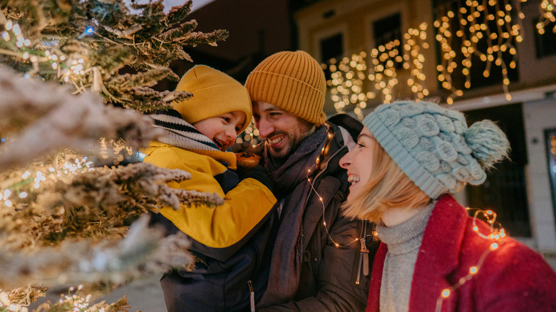 Family dressed warmly with Christmas tree and lights