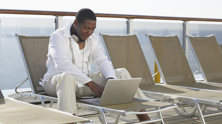 A man using a computer on a pool deck