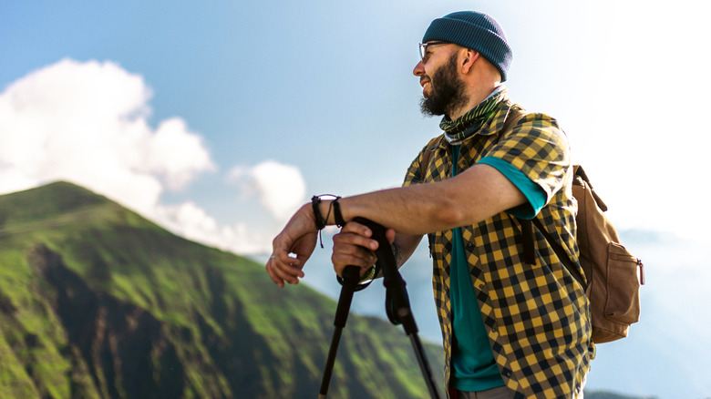 A rugged man pauses a hike to admire mountainous scenery