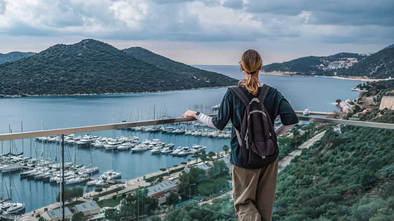 Solo traveler with backpack enjoying the view of an island with boats