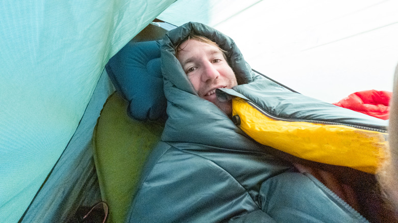 A man is bundled inside his sleeping bag in a tent