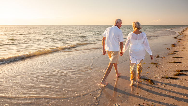 Couple holding hands, walking on beach