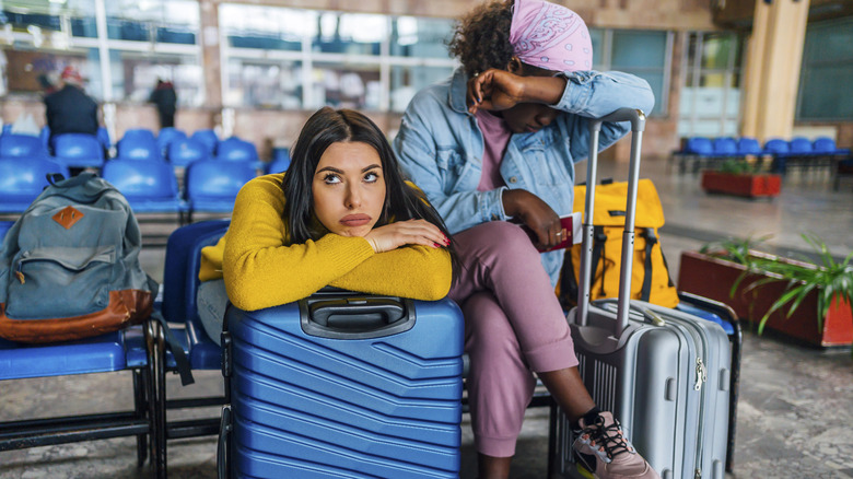 Young women with suitcases waiting for a flight.