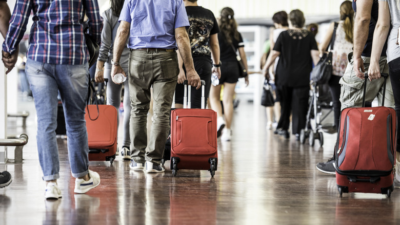 Travelers with suitcases walking through the airport.