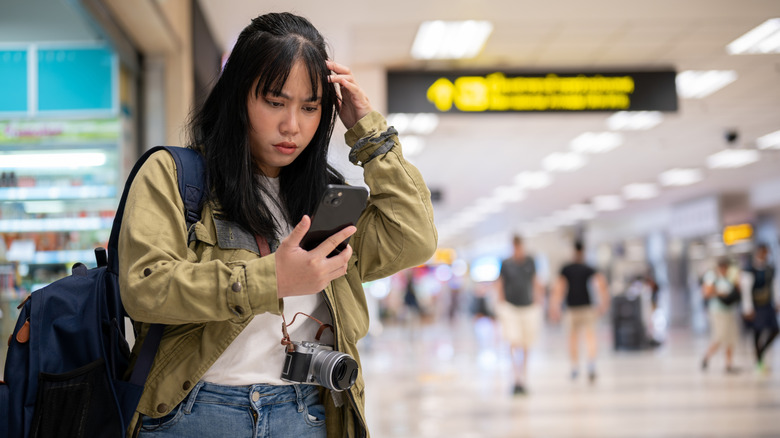 a young woman looking at her phone in confusion
