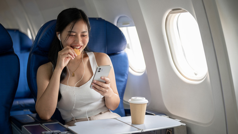 A woman eating snacks on a plane.