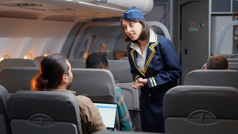 A flight attendant talking to a passenger.