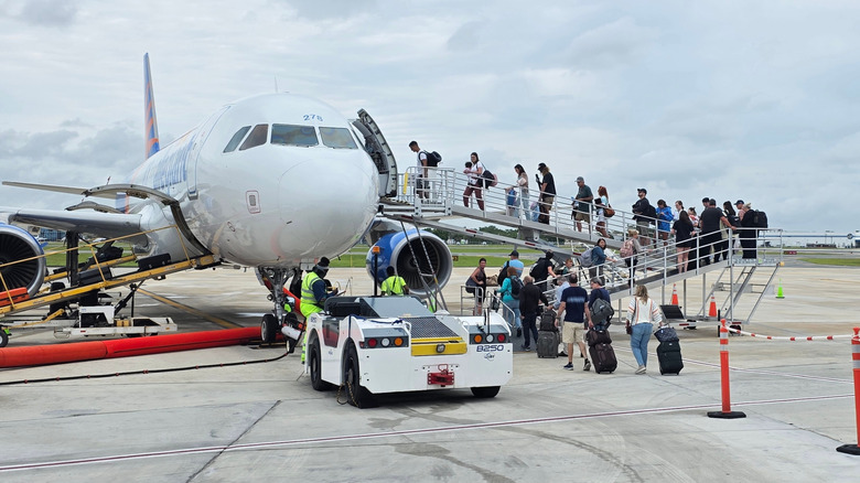Passengers climbing stairs to board Allegiant Air from a remote stand