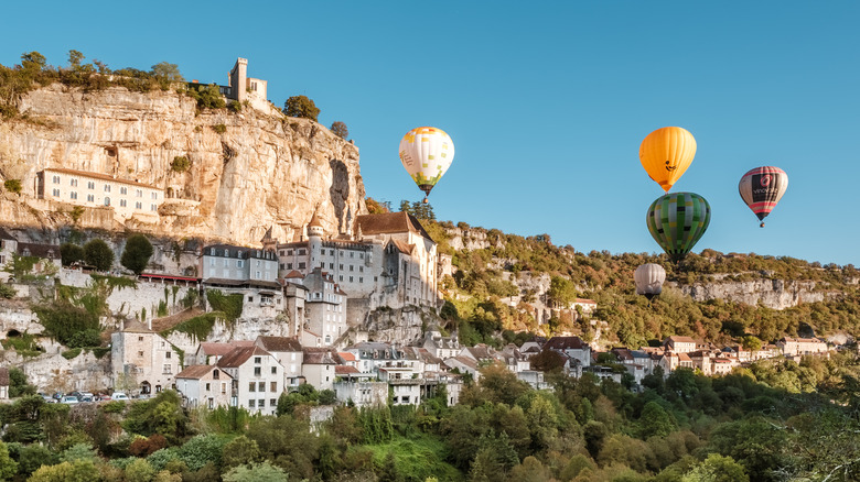 hot air ballons flying over a castle on a cliff