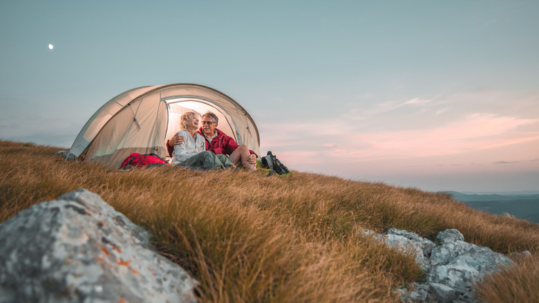 Senior couple camping hillside 