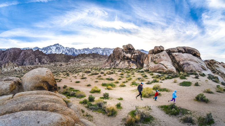 Father and kids hiking in desert with mountains in background