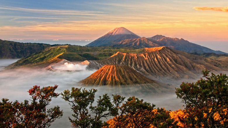 Mount Bromo and Mount Semeru rising out of mist with sunset behind