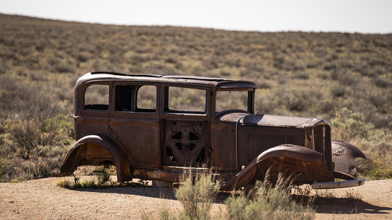 rusty frame of a vintage car without wheels, desert grasses