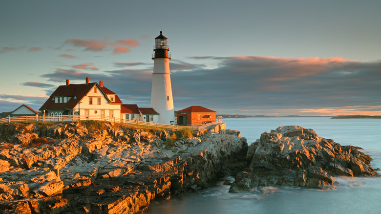 Lighthouse and houses on a rocky edge near water
