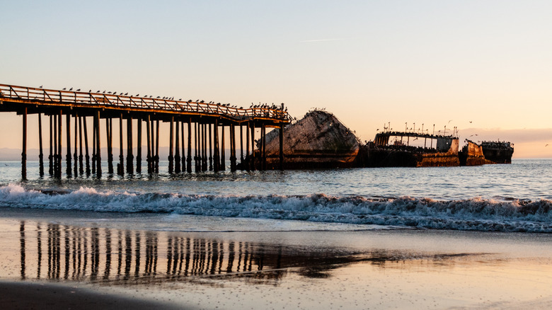 A beach shot of a destroyed pier and shipwreck near Aptos, California