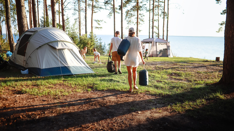family at tent campsite near trees and lake