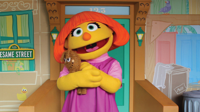 Sesame Street character Julia hugging her toy