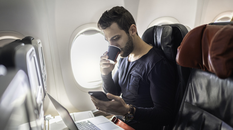 Man drinking from cup on a plane