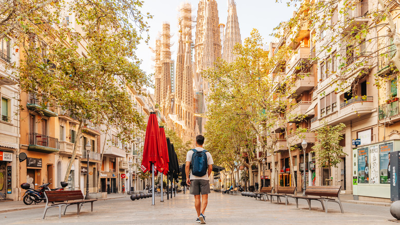 Traveler walking up a street towards La Sagrada Família in Barcelona