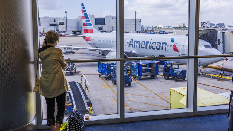 Woman watching bags loaded on an American Airlines plane