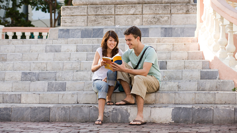 couple sitting on steps with a book