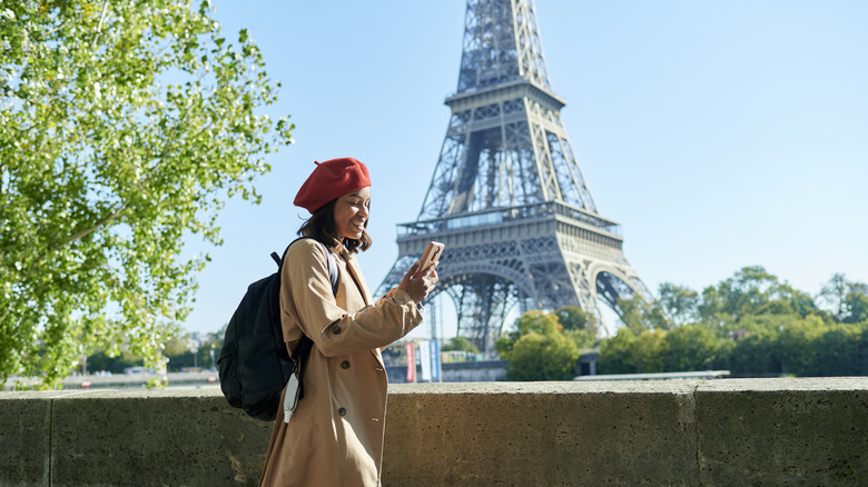 woman looking at cell phone, Eiffel Tower, trees