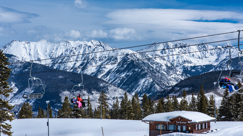 View of the snowy mountains and people in ski lifts during winter at Vail resort.