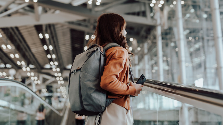 Woman with backpack and phone airport