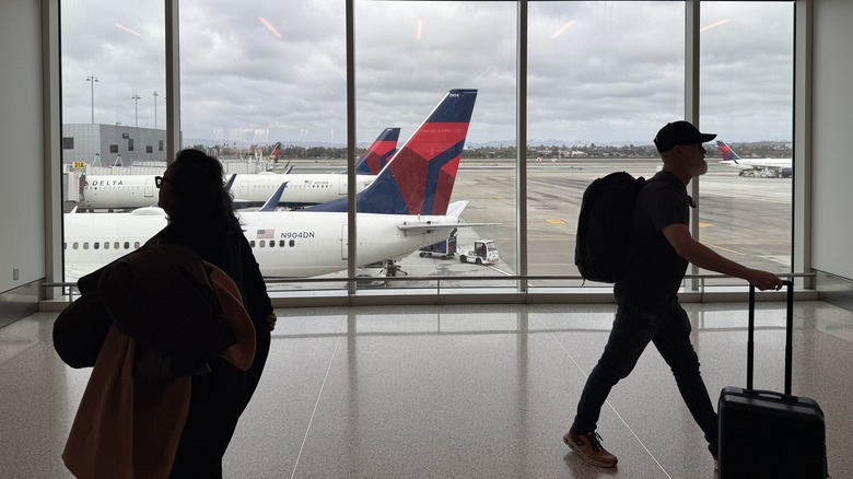 Two passengers at the airport with Delta planes in the background