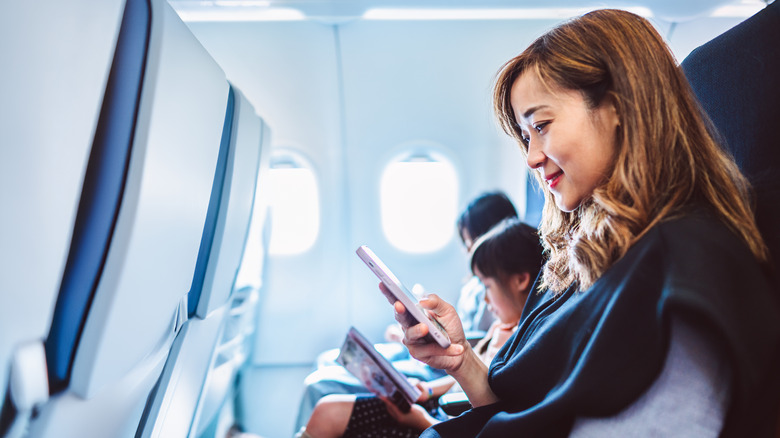 A passenger on a plane checking her smartphone