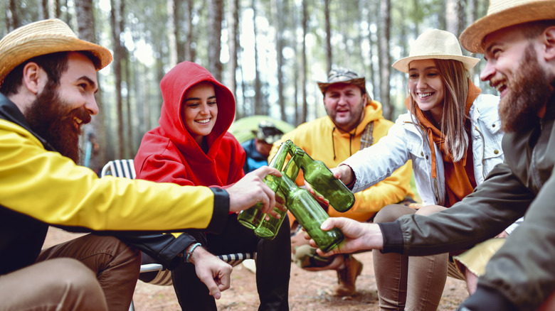 A group of campers toasting with bottled drinks.