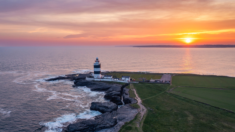 A black and white lighthouse at the end of a small peninsula