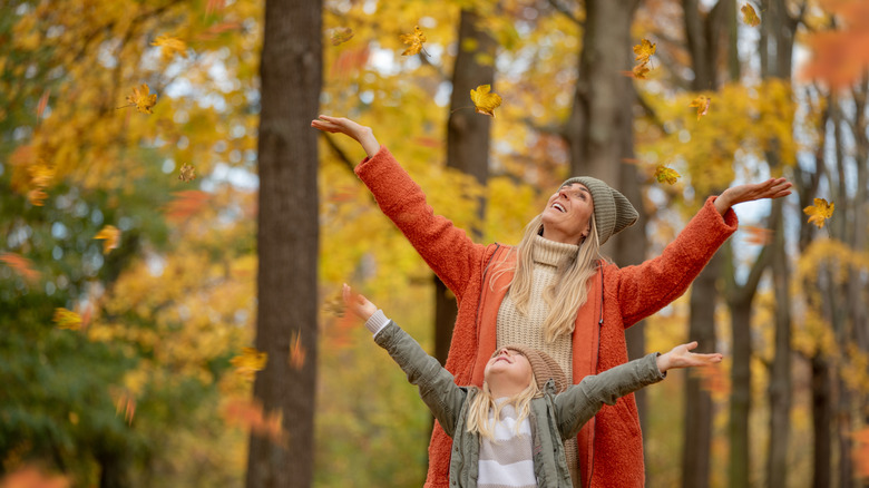 A woman and child in a forest with fall colors.