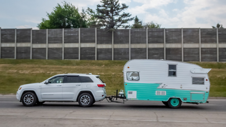 A small SUV towing a Shasta trailer.