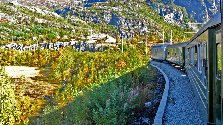 A train curving around a bend in a rocky landscape