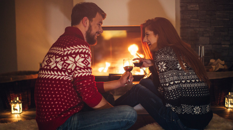 Couple with wine by fireplace