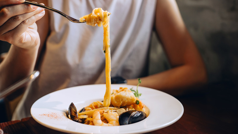 A person eating seafood pasta.
