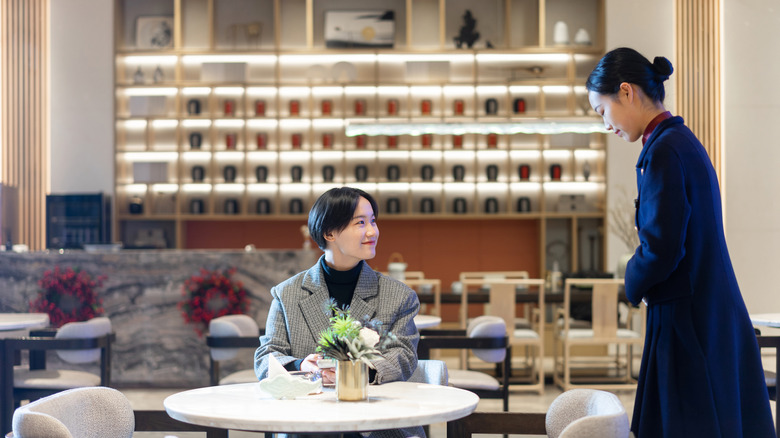 A server bows to a customer at an upscale Japanese restaurant