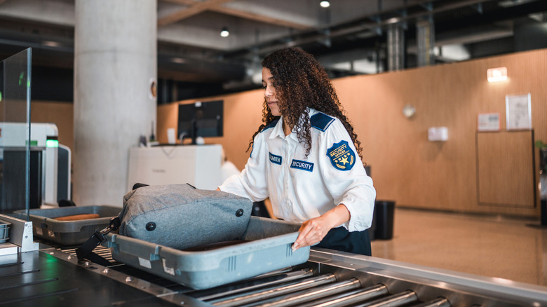 tsa agent pushing bin with luggage