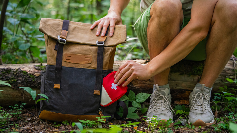 person pulling medical kit out of backpack
