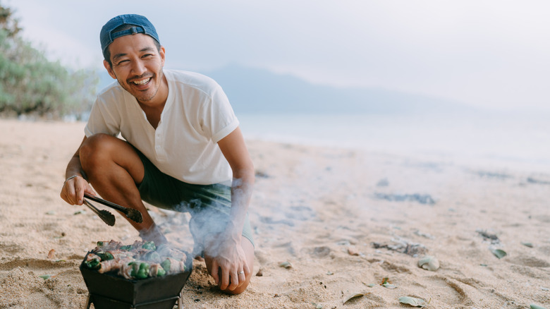Camper cooking over stove on the beach