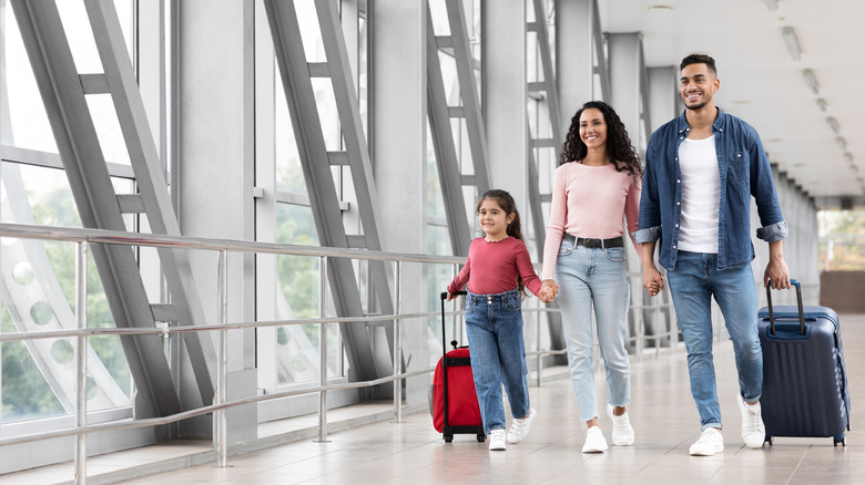 A happy family walking through the airport with suitcases