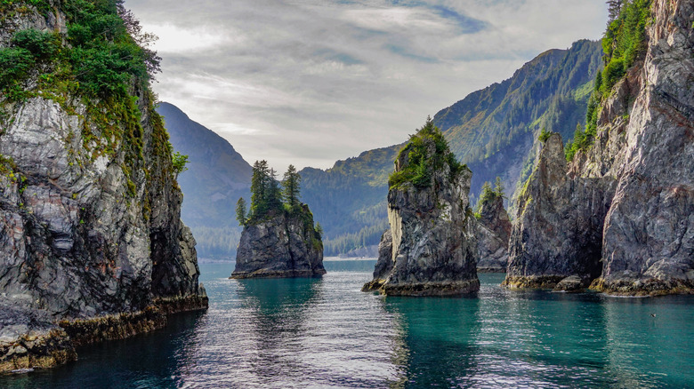 rock formations in an ocean bay with mountains in the distance