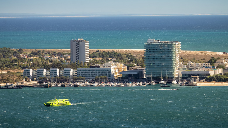 An aerial view of a ferry in the water with buildings surrounded by blue water