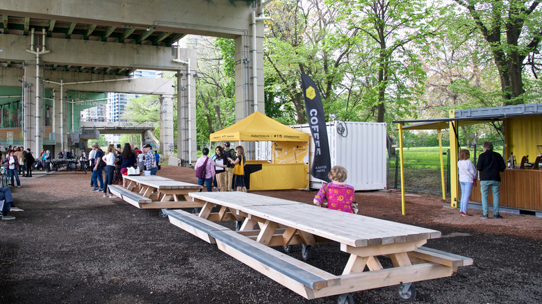 Picnickers hang out at tables on the Bentway in Toronto